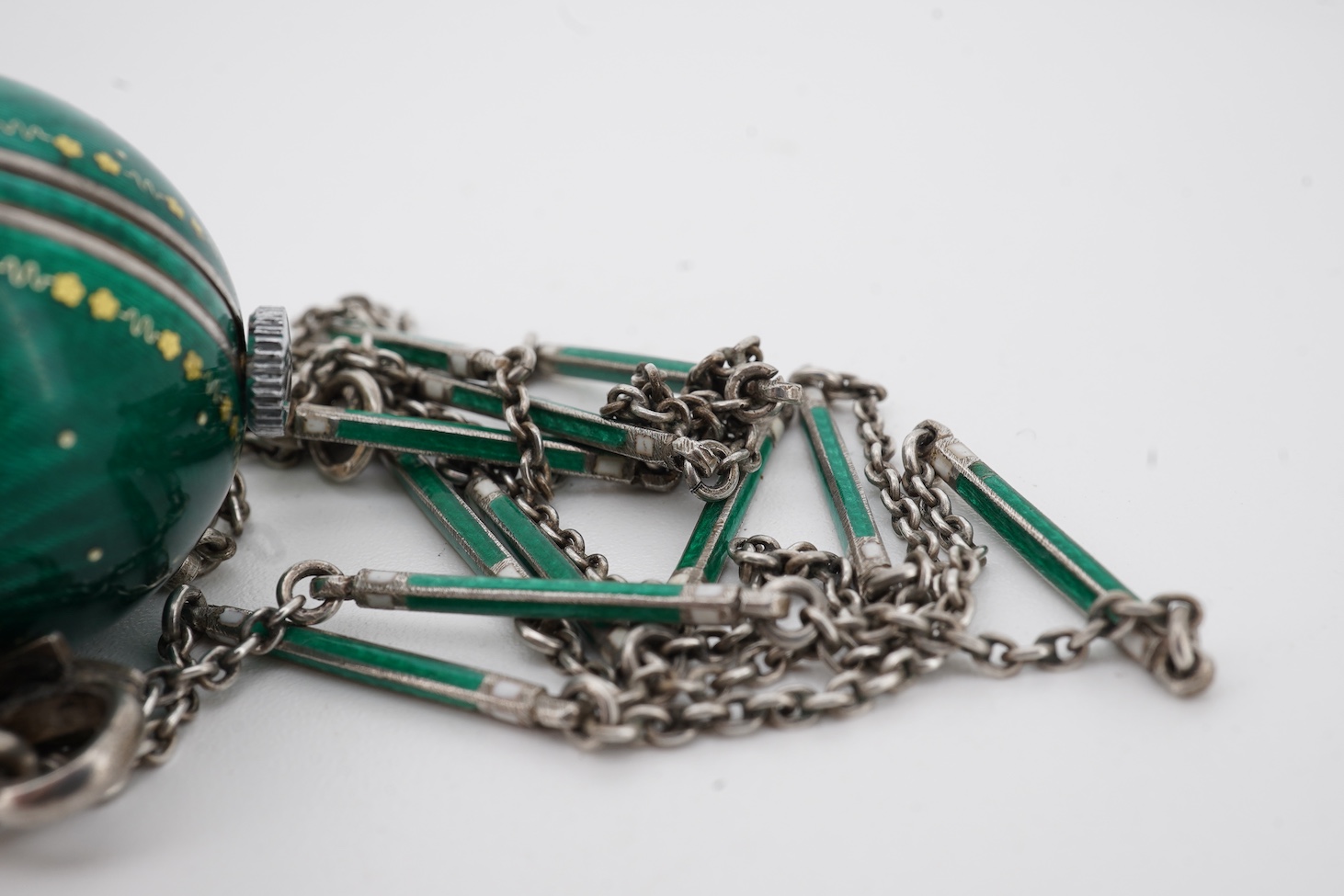 An early to mid 20th century 925 and green enamel globe pendant watch, with Arabic dial and gilt highlights, diameter 22mm, on a 925 and green and white enamel baton link chain, 62cm.